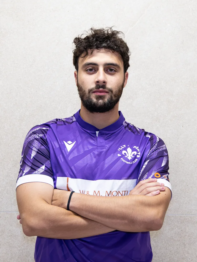 Un joueur de la première équipe, bras croisés, maillot violet
