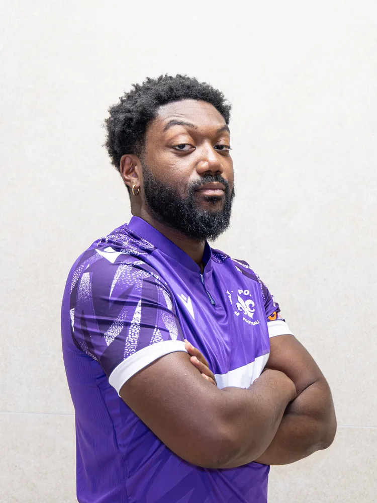 Un joueur de la première équipe, bras croisés, maillot violet